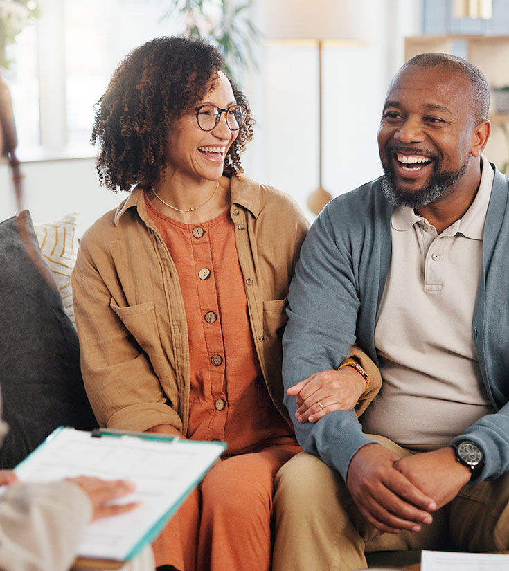 http://A%20young%20couple%20smiles%20while%20out%20of%20focus%20a%20financial%20planner%20holds%20a%20report%20on%20a%20clipboard