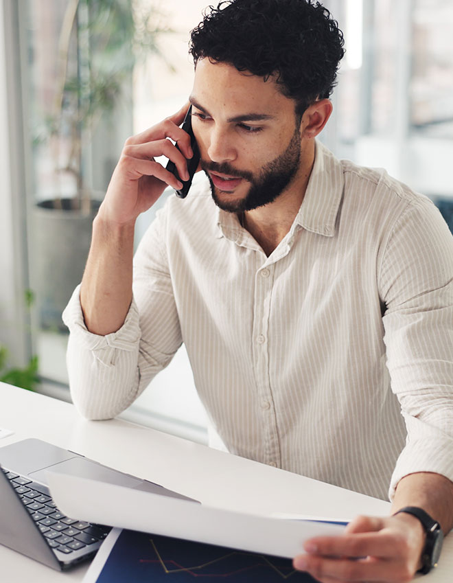 http://Man%20reviews%20financial%20documents%20while%20on%20the%20phone